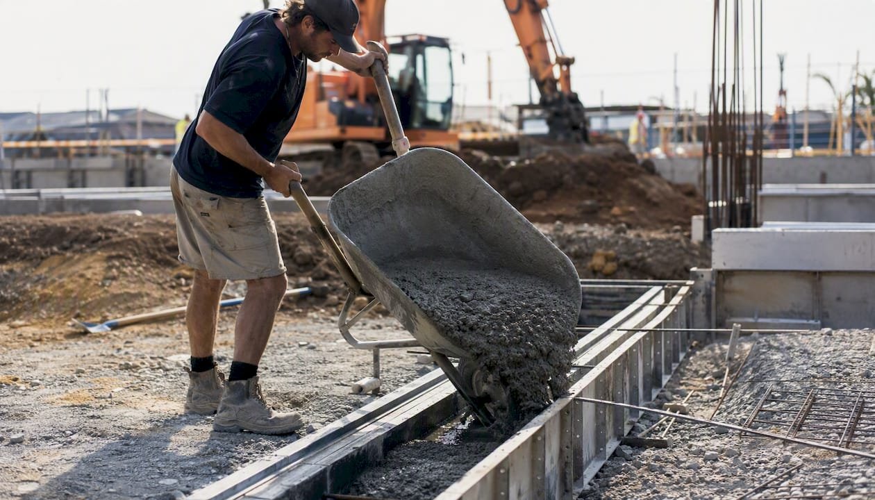 Worker pouring fiber reinforced concrete into formwork