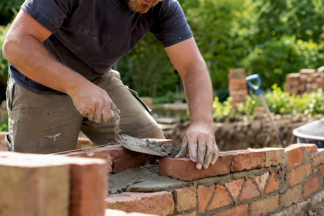 Mason spreading mortar on decorative brick wall