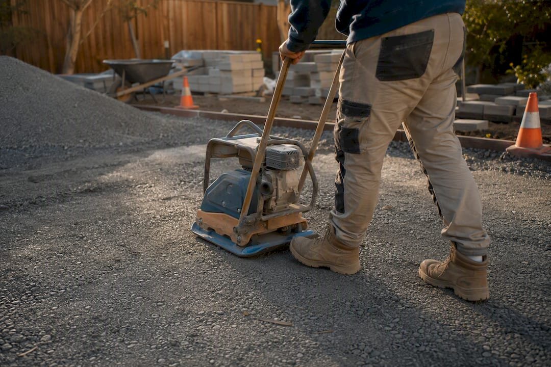 Compactor smoothing crushed rock base in garden